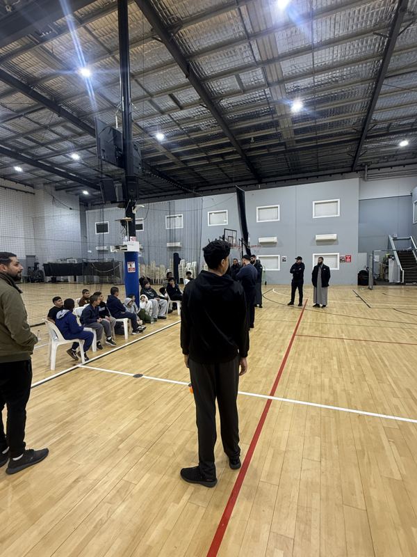 A coach watching the court under the hall lights