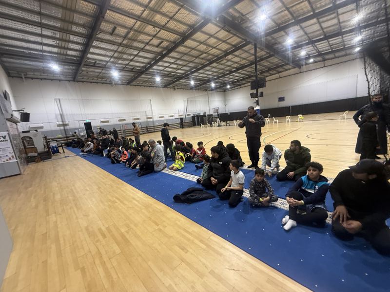 Boys sitting on the mats at the side of the hall